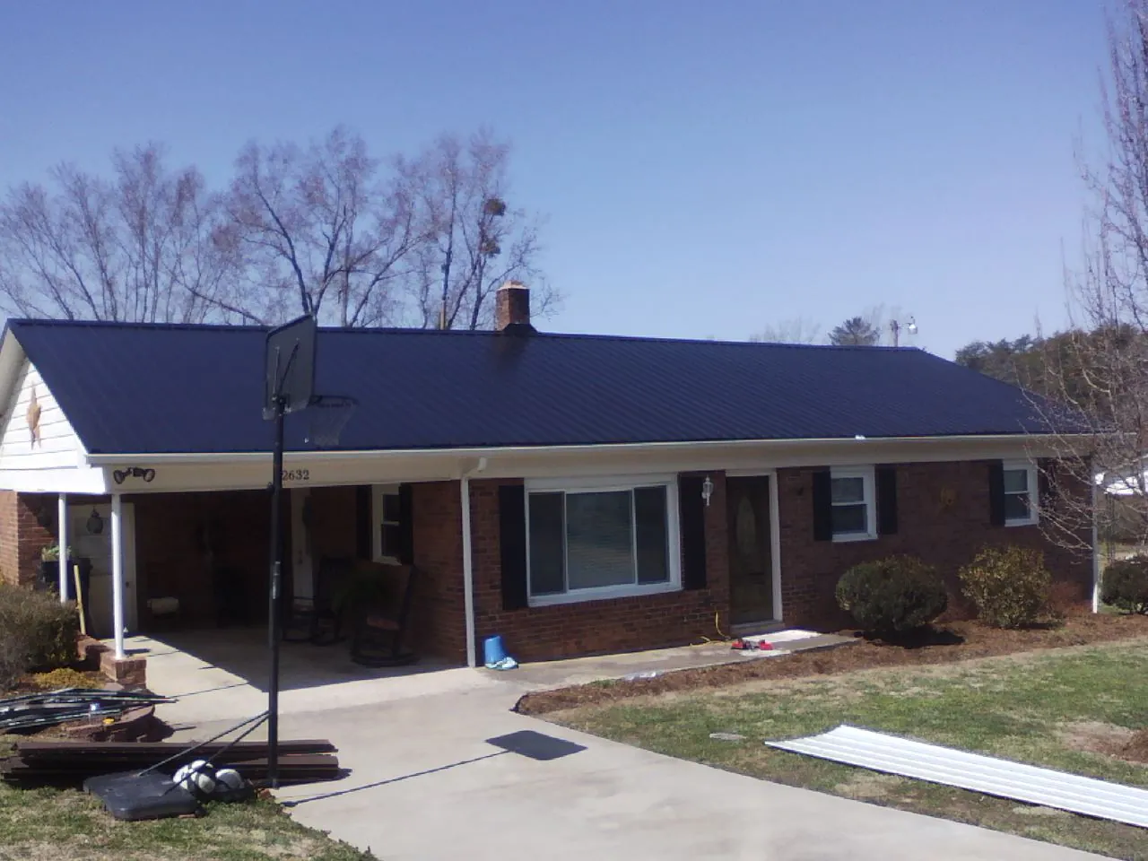 Finished dark blue metal roof on a brick ranch with a carport in Frankfort